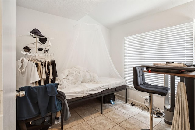 bedroom featuring tile patterned floors, a textured ceiling, and baseboards