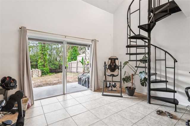 interior space with light tile patterned flooring, stairway, high vaulted ceiling, and baseboards