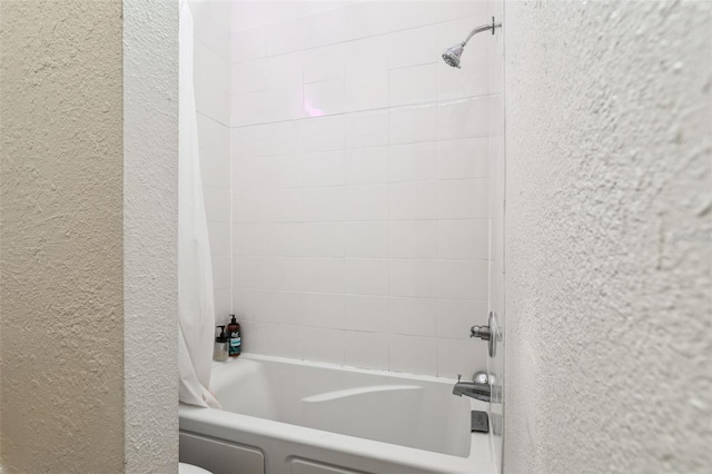 bathroom featuring shower / bathtub combination with curtain and a textured wall