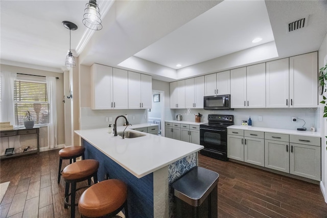 kitchen with visible vents, wood finish floors, black appliances, a raised ceiling, and a sink