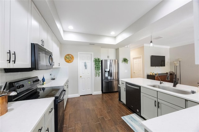 kitchen featuring dark wood finished floors, a sink, decorative backsplash, black appliances, and light countertops