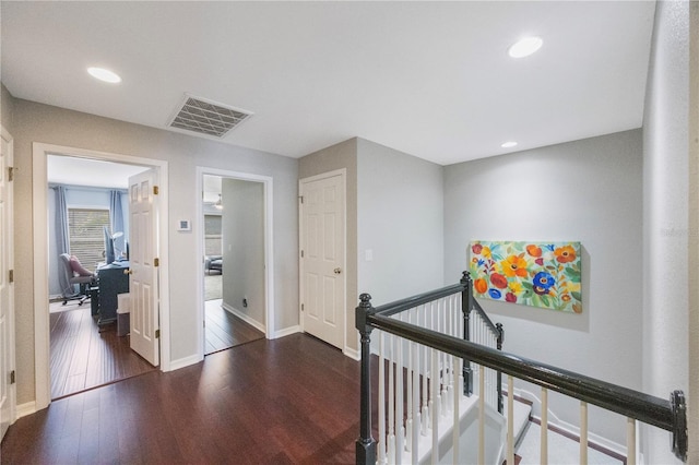 hall featuring visible vents, dark wood-type flooring, baseboards, an upstairs landing, and recessed lighting