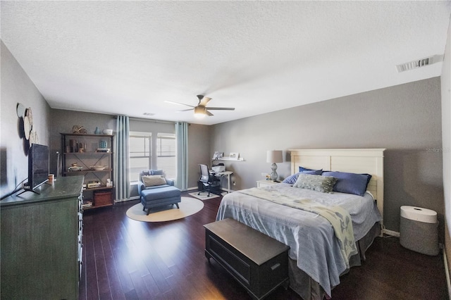 bedroom with visible vents, a textured ceiling, dark wood-type flooring, and ceiling fan