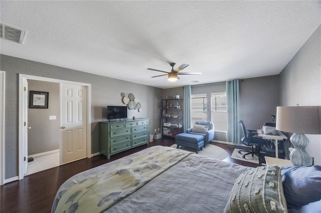 bedroom with a ceiling fan, wood finished floors, visible vents, baseboards, and a textured ceiling