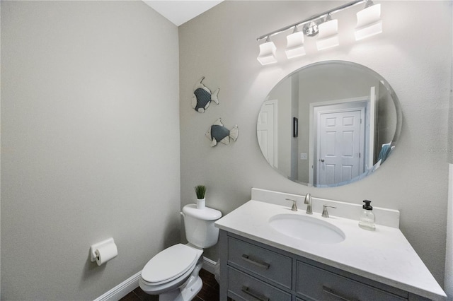 bathroom featuring toilet, vanity, and baseboards