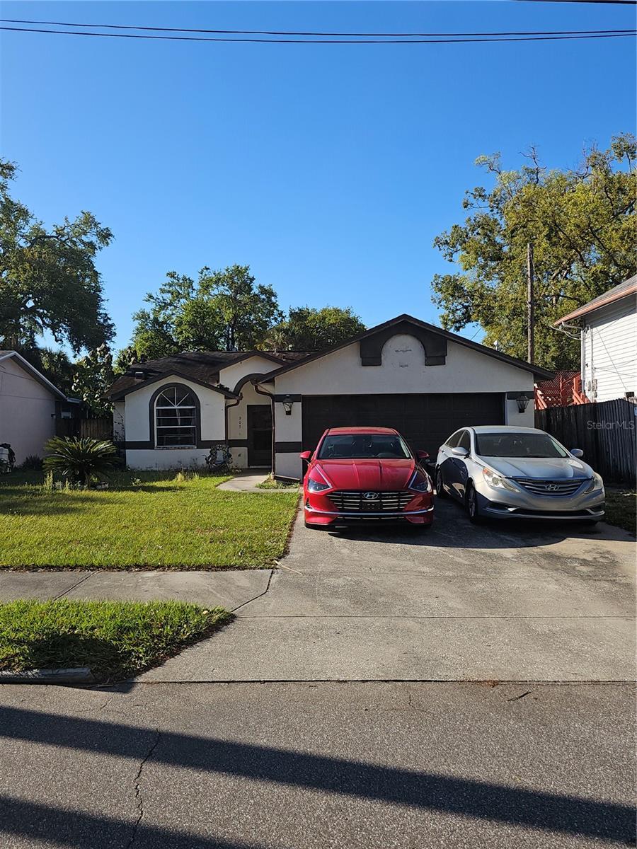 ranch-style house featuring fence, an attached garage, stucco siding, concrete driveway, and a front lawn