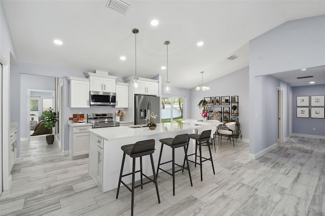 kitchen featuring visible vents, a kitchen bar, stainless steel appliances, white cabinetry, and a kitchen island with sink