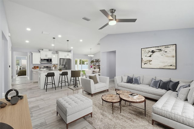 living area with visible vents, light wood finished floors, recessed lighting, vaulted ceiling, and ceiling fan with notable chandelier