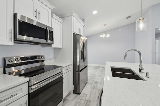 kitchen with visible vents, a sink, stainless steel appliances, white cabinets, and decorative light fixtures