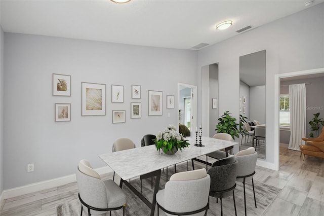 dining area featuring light wood-style floors, baseboards, and visible vents