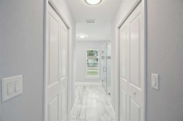 hall featuring visible vents and baseboards