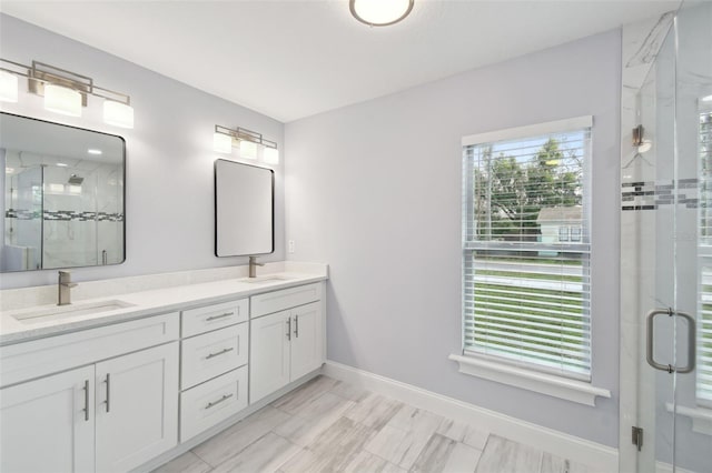 full bath with double vanity, a stall shower, baseboards, and a sink