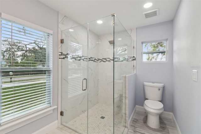 bathroom with a marble finish shower, visible vents, baseboards, and toilet