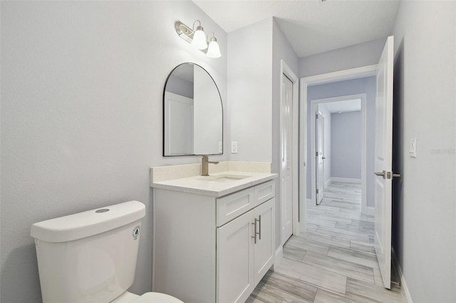 half bathroom with toilet, vanity, and baseboards