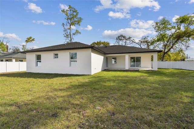 back of house featuring a yard, fence, and stucco siding