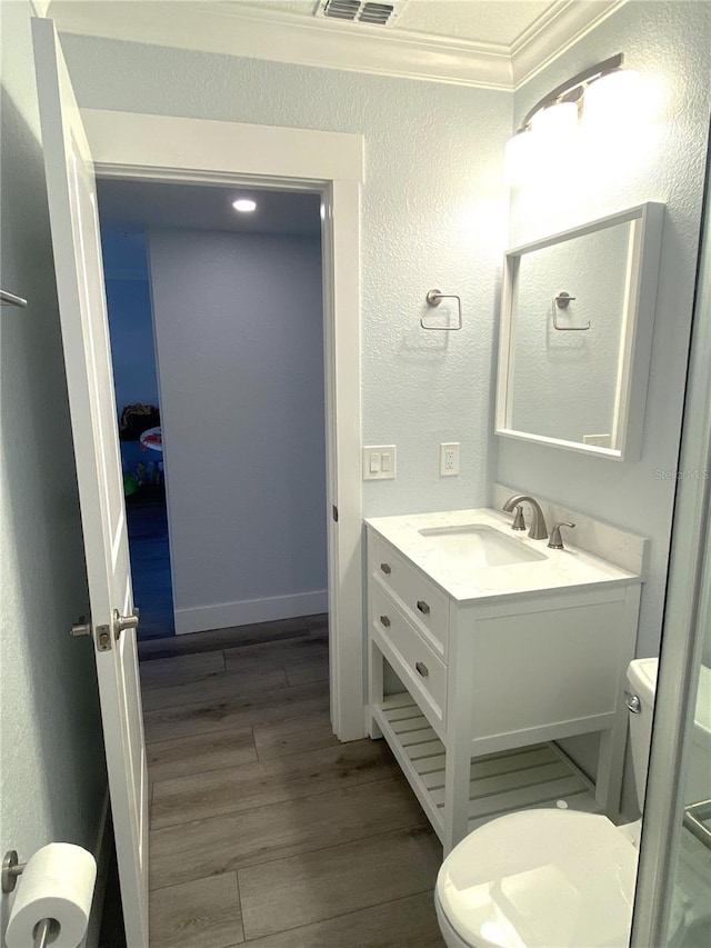 bathroom with toilet, vanity, a textured wall, and wood finished floors