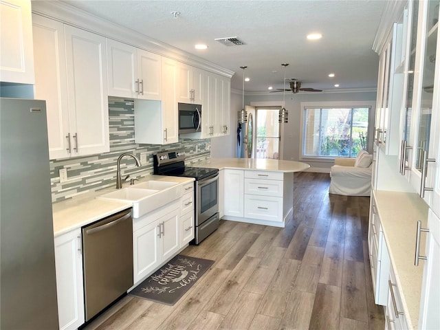 kitchen with a sink, appliances with stainless steel finishes, a peninsula, and light countertops