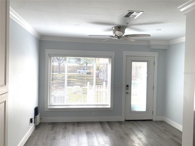 doorway featuring visible vents, a textured ceiling, wood finished floors, crown molding, and baseboards