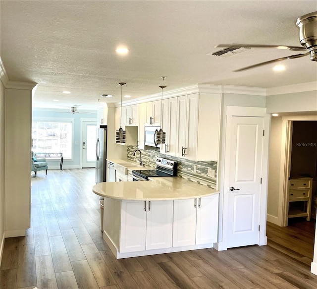 kitchen featuring wood finished floors, a ceiling fan, stainless steel appliances, decorative backsplash, and light countertops