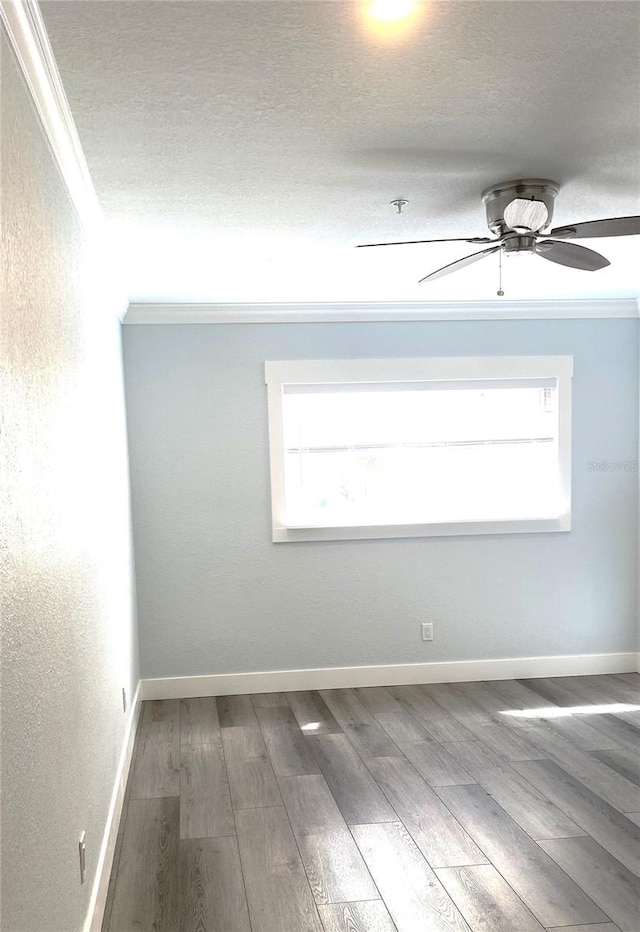 empty room with ornamental molding, a healthy amount of sunlight, and wood finished floors