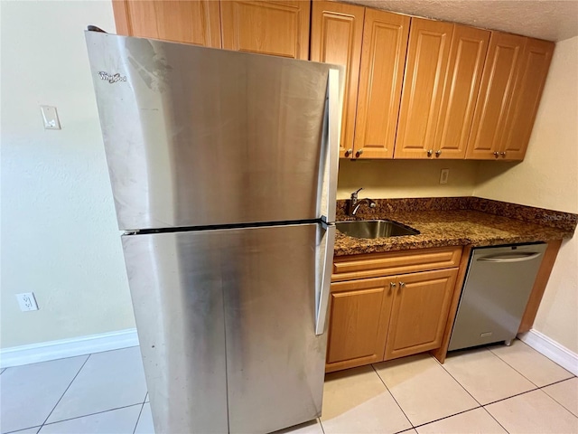 5221 Bayshore Blvd Unit 29, Tampa, FL 33611 - kitchen with dark stone countertops, baseboards, light tile patterned flooring, a sink, and appliances with stainless steel finishes