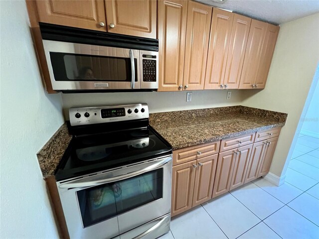 5221 Bayshore Blvd Unit 29, Tampa, FL 33611 - kitchen with light tile patterned flooring, dark stone countertops, stainless steel appliances, and baseboards