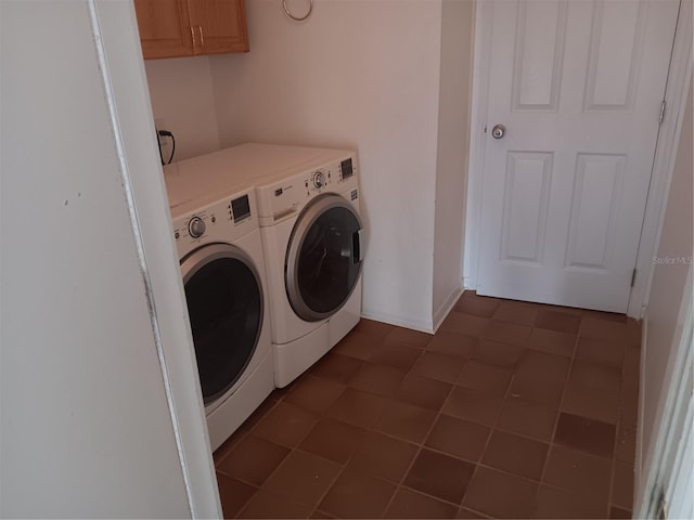 clothes washing area featuring baseboards, cabinet space, and washing machine and dryer