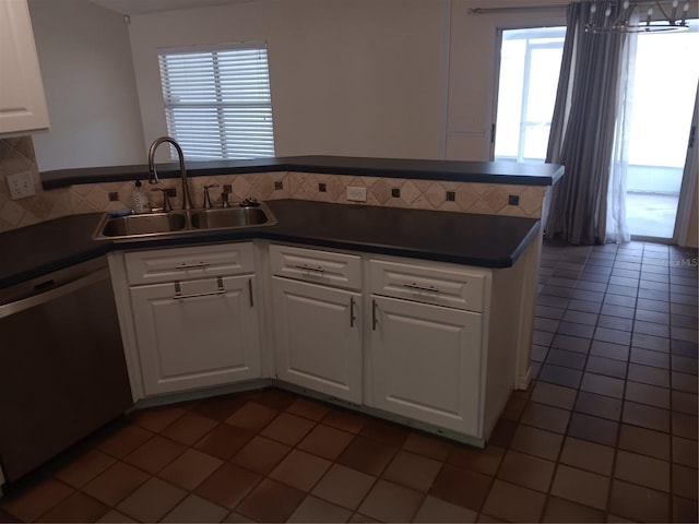 kitchen featuring dark countertops, dishwasher, a peninsula, white cabinetry, and a sink