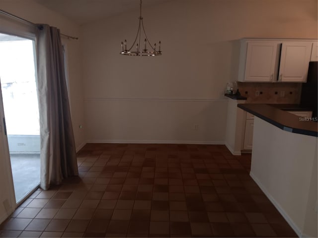 unfurnished dining area featuring a wealth of natural light, baseboards, and a chandelier