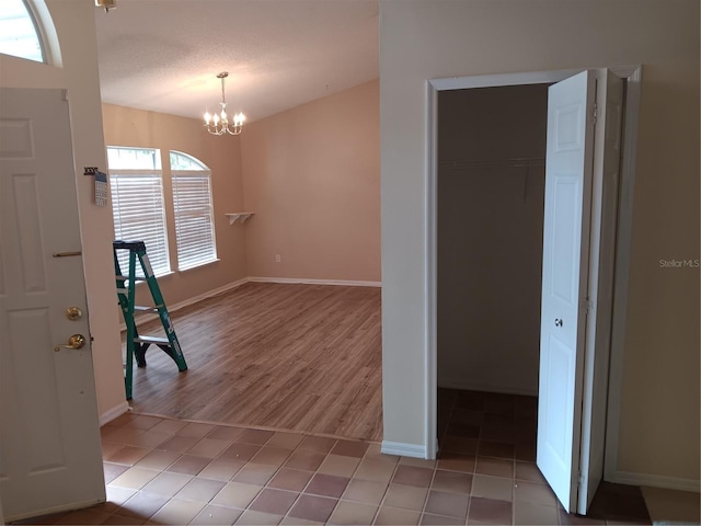 interior space with tile patterned flooring, a notable chandelier, and baseboards