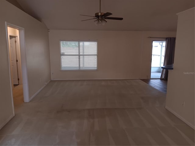 spare room featuring light carpet, a ceiling fan, baseboards, and vaulted ceiling