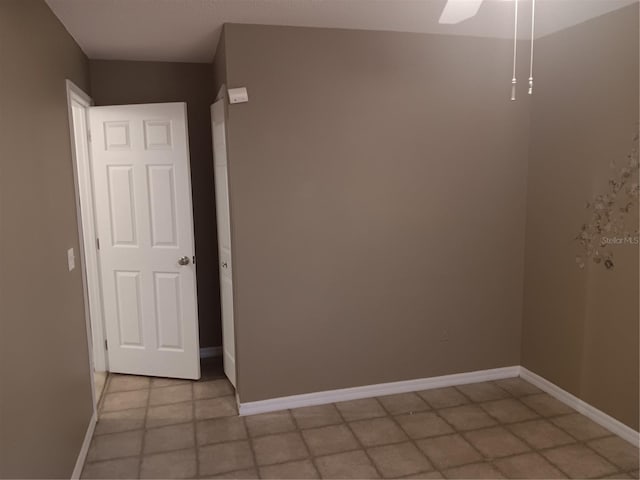 empty room with ceiling fan and baseboards