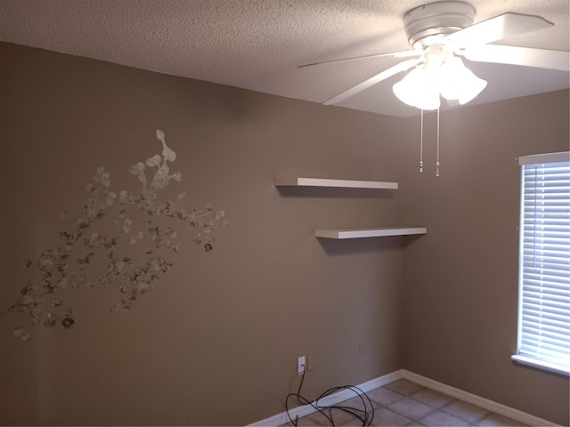 unfurnished room with light tile patterned floors, baseboards, a textured ceiling, and a ceiling fan