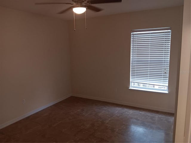 empty room featuring plenty of natural light, a ceiling fan, and baseboards