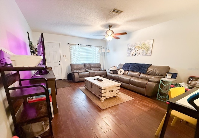 living area featuring ceiling fan, wood finished floors, visible vents, and a textured ceiling