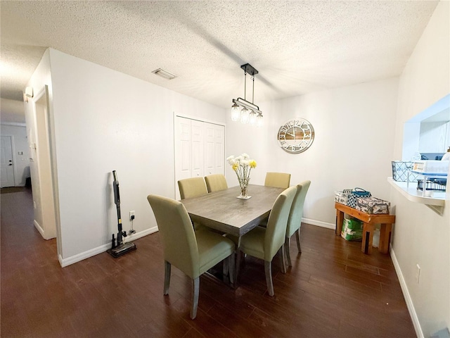 dining room with baseboards, wood finished floors, visible vents, and a textured ceiling