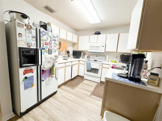 kitchen with white appliances, visible vents, light countertops, a textured ceiling, and light wood-type flooring