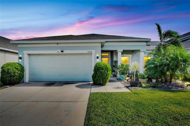 view of front facade with a garage, a front yard, driveway, and stucco siding