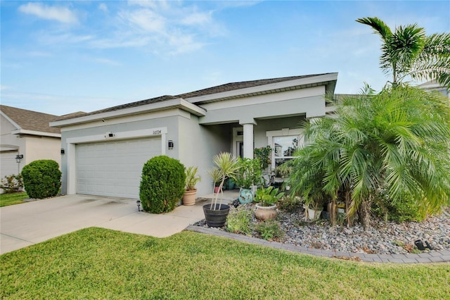 view of front of house with concrete driveway, a front lawn, a garage, and stucco siding