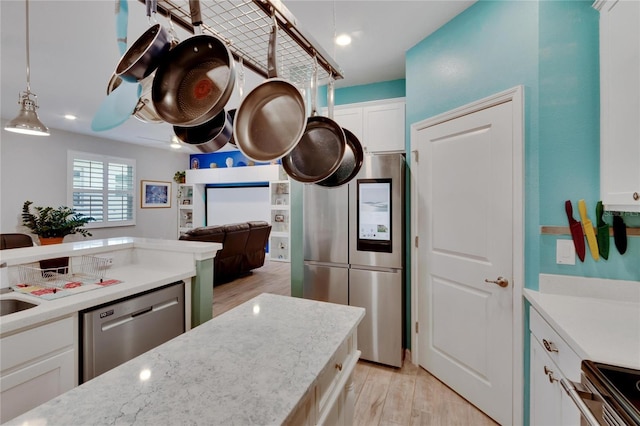 kitchen with decorative light fixtures, open floor plan, white cabinetry, stainless steel appliances, and light wood-style floors