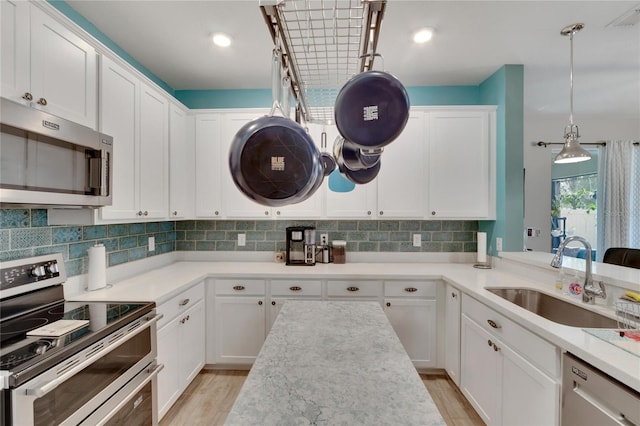 kitchen featuring a sink, light wood-style floors, appliances with stainless steel finishes, white cabinetry, and backsplash