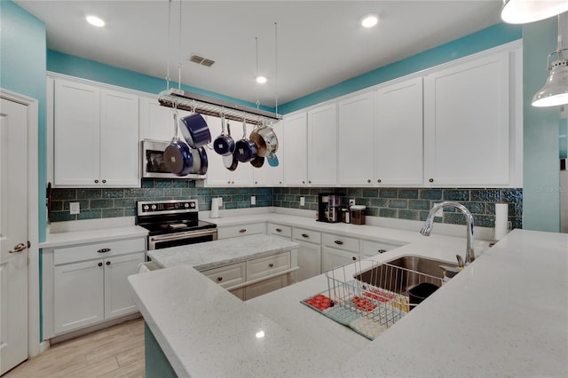 kitchen with light wood finished floors, backsplash, appliances with stainless steel finishes, white cabinetry, and a sink