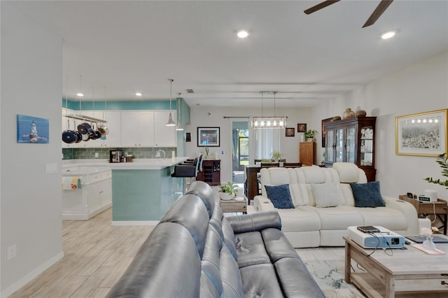 living area featuring recessed lighting, ceiling fan with notable chandelier, and light wood-style floors