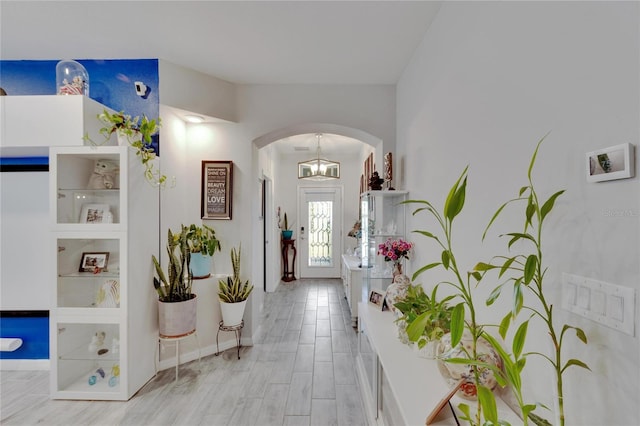 foyer featuring light wood-style floors, arched walkways, and baseboards