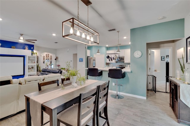 dining space with arched walkways, recessed lighting, light wood finished floors, and a ceiling fan