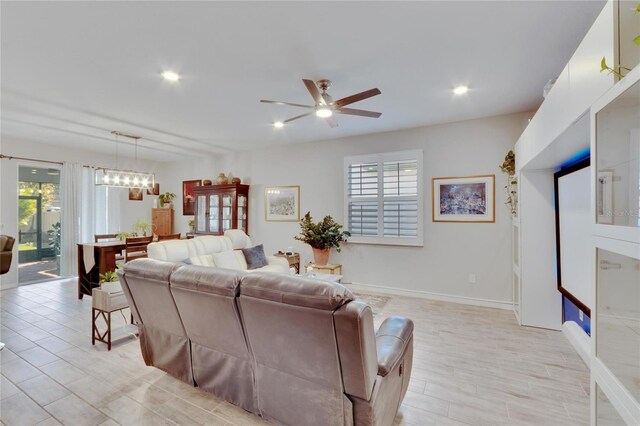 living room with recessed lighting, baseboards, and ceiling fan with notable chandelier