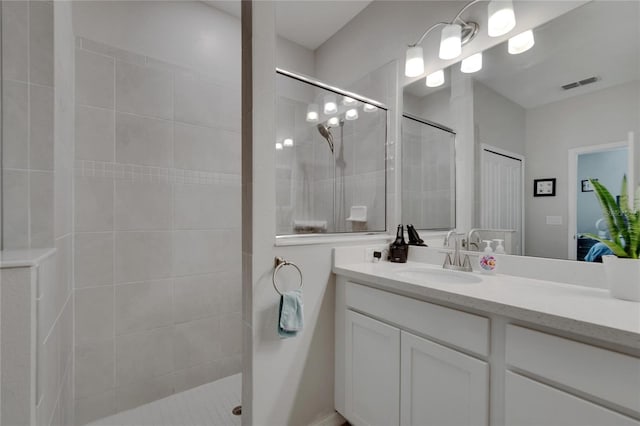 bathroom featuring vanity, visible vents, and walk in shower