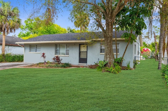 ranch-style home with a front yard, fence, and stucco siding