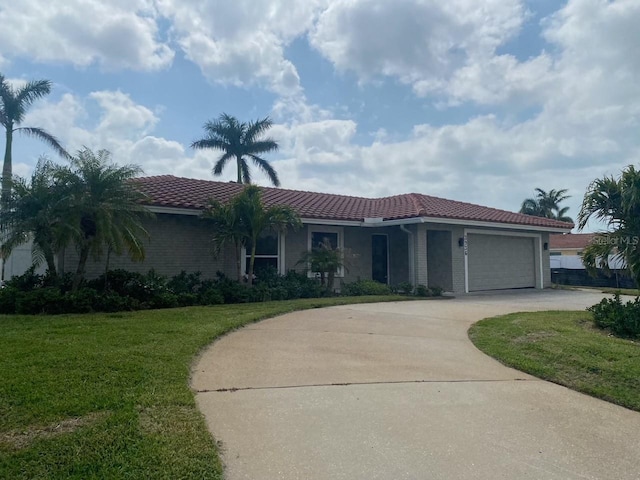 view of front of house with brick siding, a tile roof, concrete driveway, a front yard, and an attached garage