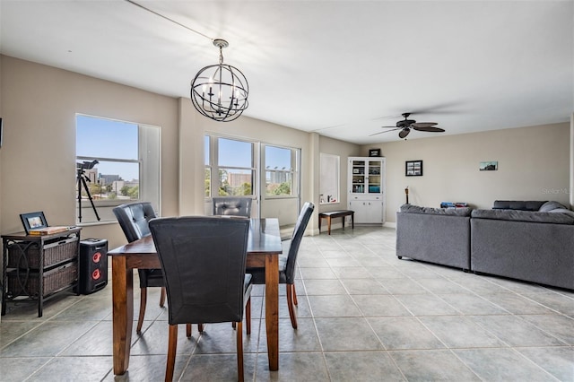 dining area with light tile patterned flooring, ceiling fan with notable chandelier, and baseboards